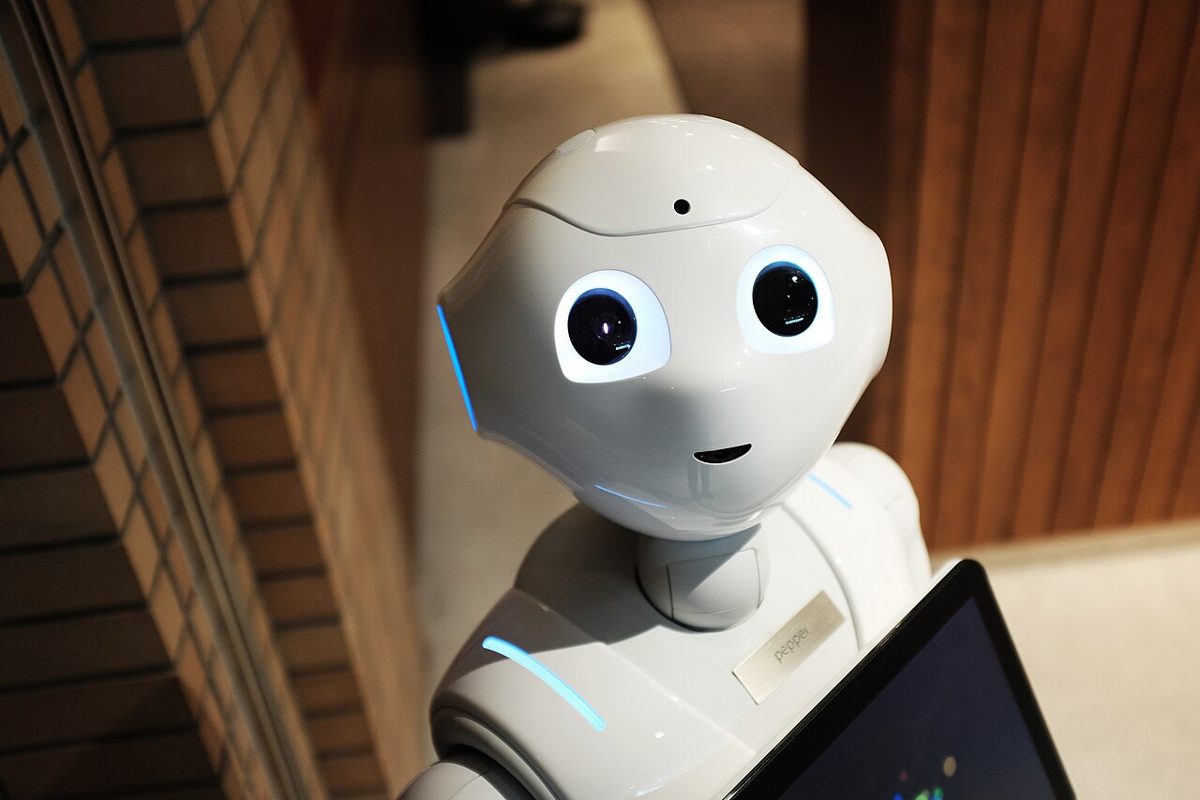 Robot humanoide de color blanco junto a una pantalla