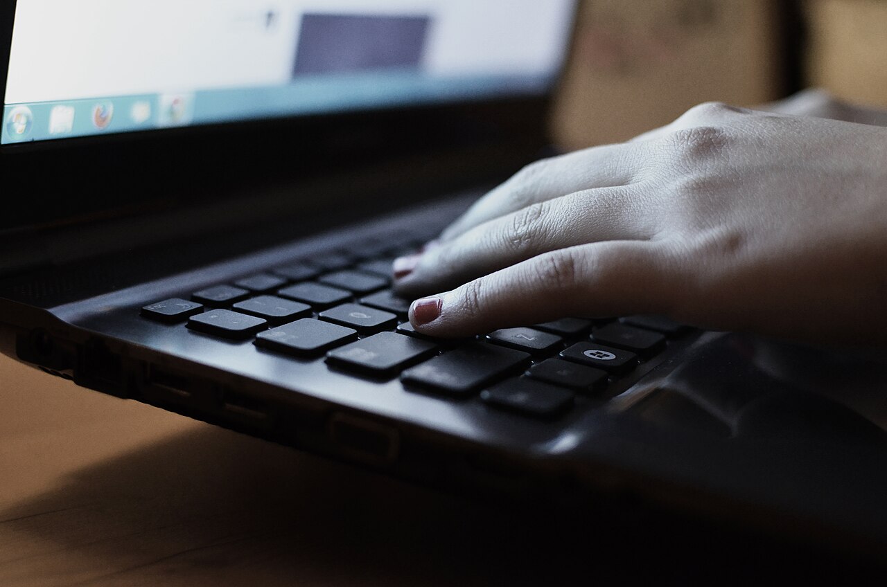 Mano escribiendo en un portátil mientras se planea el contenido de redes sociales