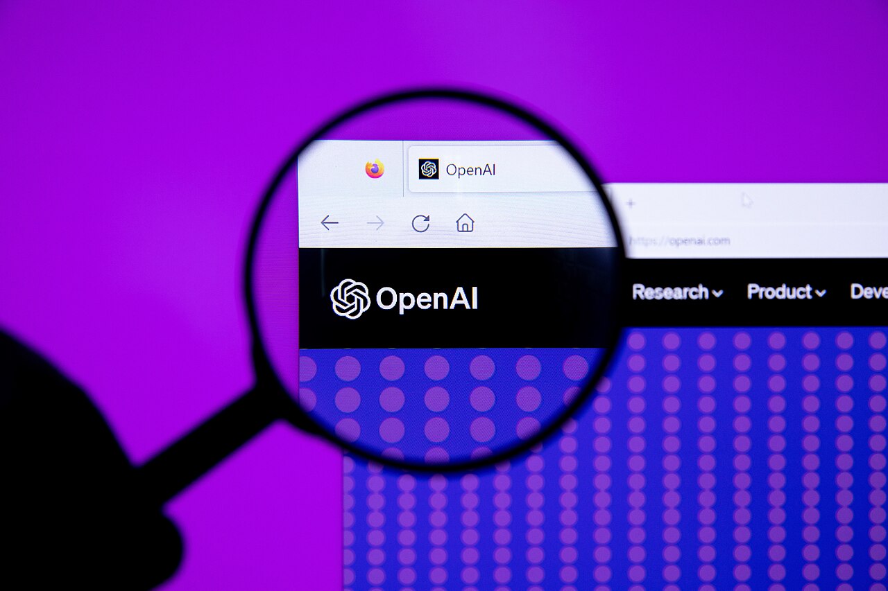 Logo de OpenAI, la empresa creadora de ChatGPT, visto a través de una lupa