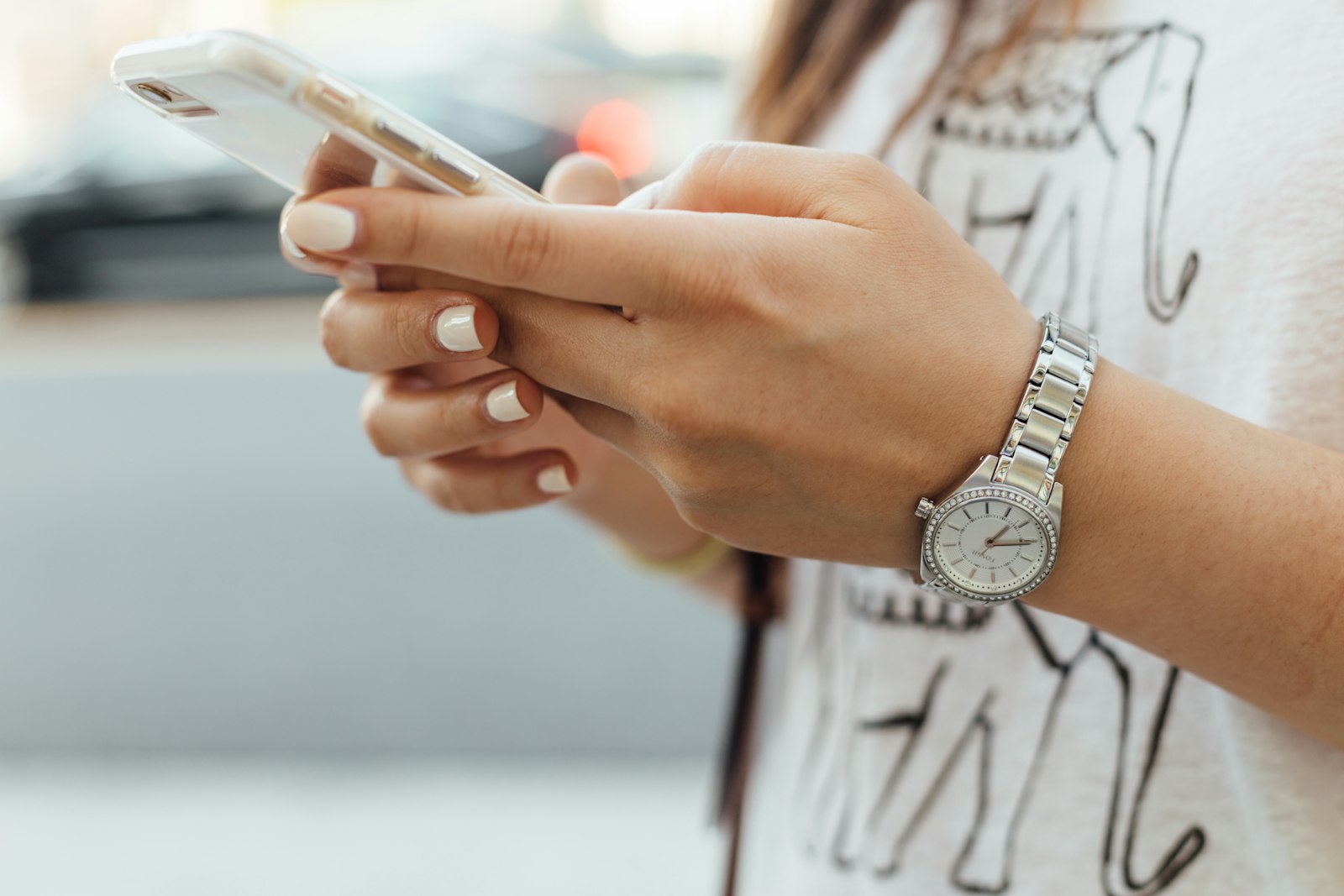 Mujer sosteniendo un iPhone durante el día, usando WhatsApp