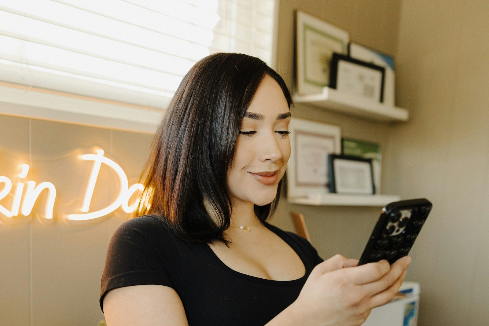 Mujer atendiendo a clientes en un mostrador mientras sostiene un celular